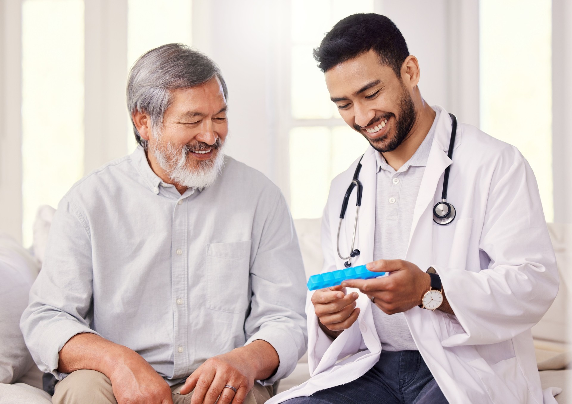 Shot of a doctor holding a pill box while talking to a senior patient