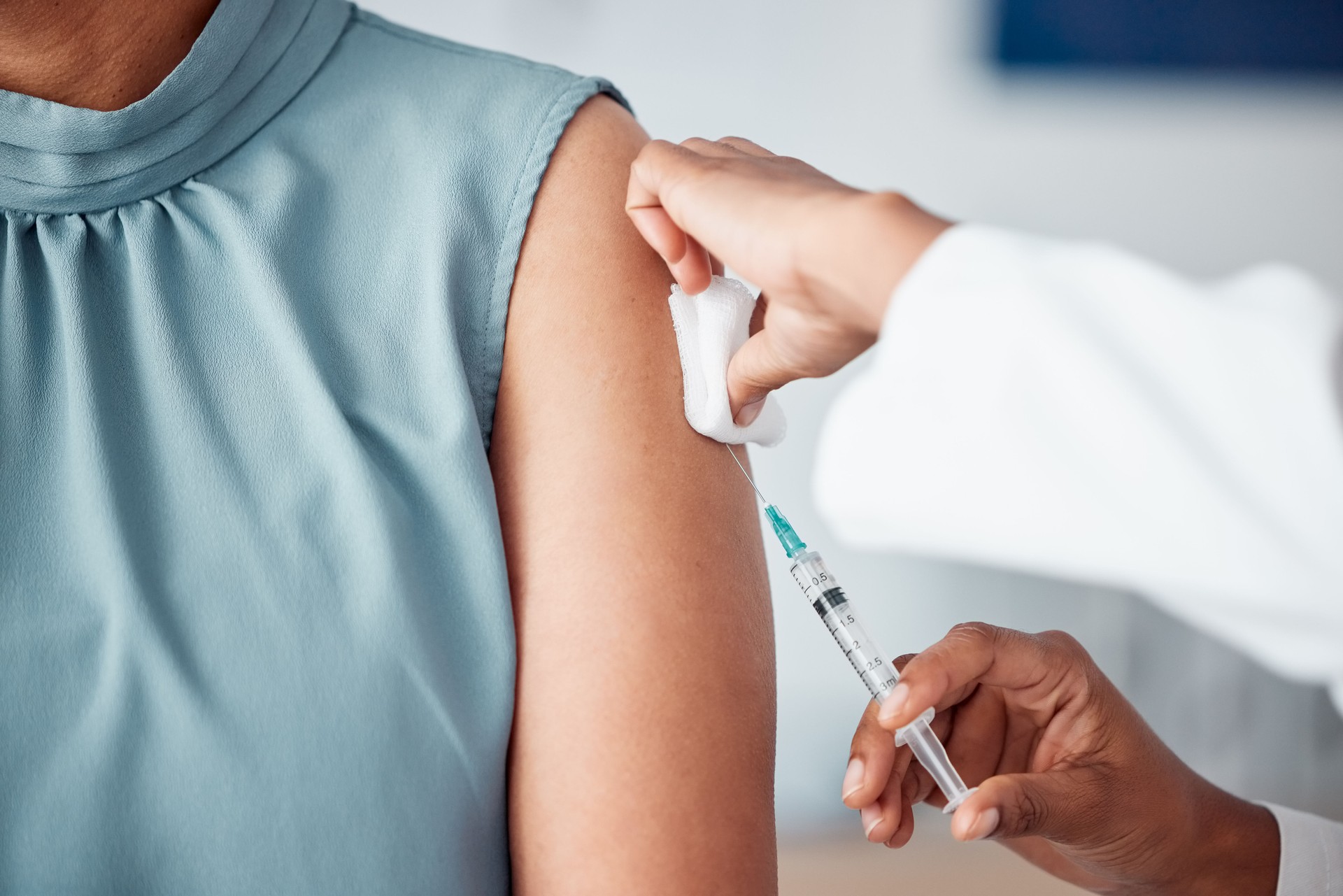 Hands, medical and doctor with patient for vaccine in a clinic for healthcare treatment for prevention. Closeup of a nurse doing a vaccination injection with a needle syringe in a medicare hospital.